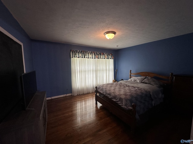 bedroom with wood finished floors, a textured ceiling, and baseboards