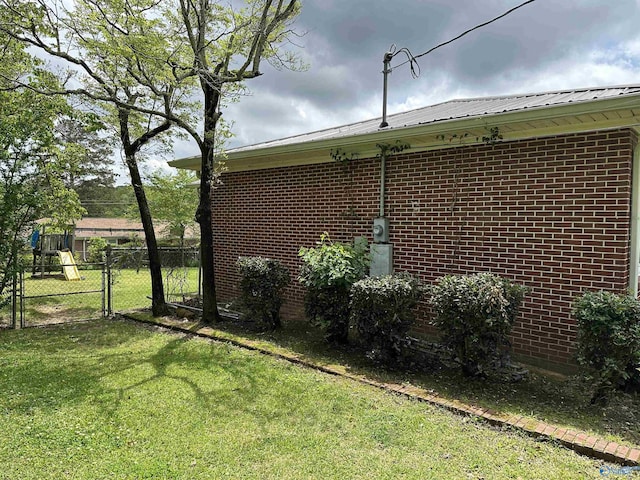 view of property exterior featuring brick siding, metal roof, and a gate