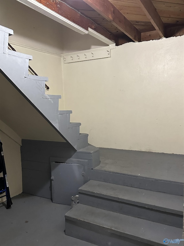 staircase with concrete flooring and beam ceiling