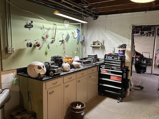 kitchen with concrete flooring, dark countertops, and concrete block wall