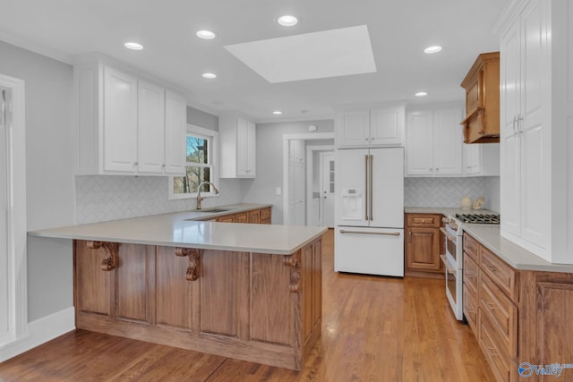 kitchen with a peninsula, light wood-style flooring, a skylight, light countertops, and high quality appliances