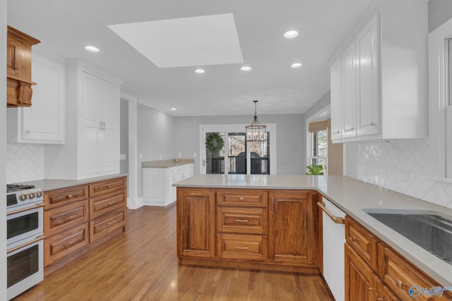 kitchen with white appliances, light wood-style flooring, white cabinets, and light countertops