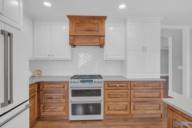 kitchen with high end white refrigerator, double oven range, white cabinets, and light countertops