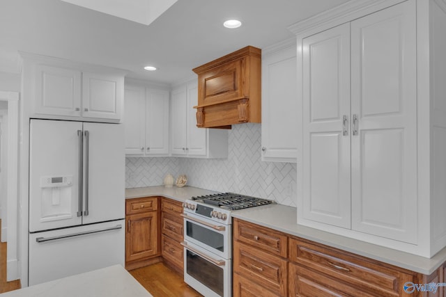 kitchen featuring white cabinetry, light countertops, high end appliances, and tasteful backsplash