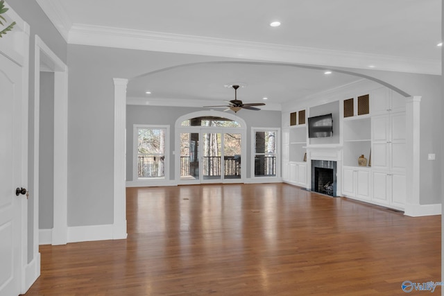 unfurnished living room with baseboards, ceiling fan, ornamental molding, a premium fireplace, and wood finished floors