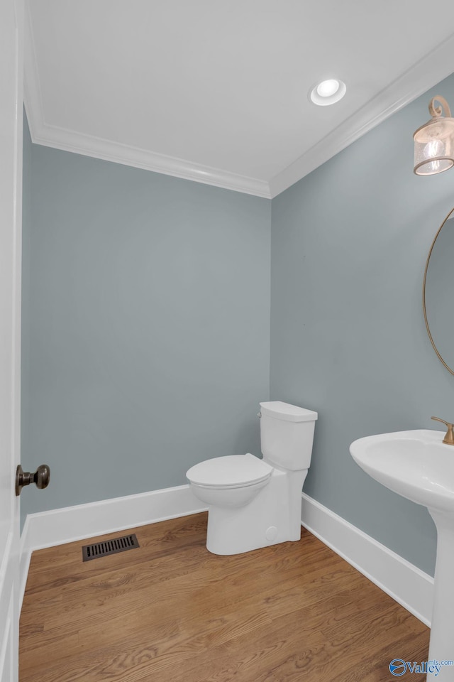 bathroom with visible vents, toilet, wood finished floors, crown molding, and baseboards