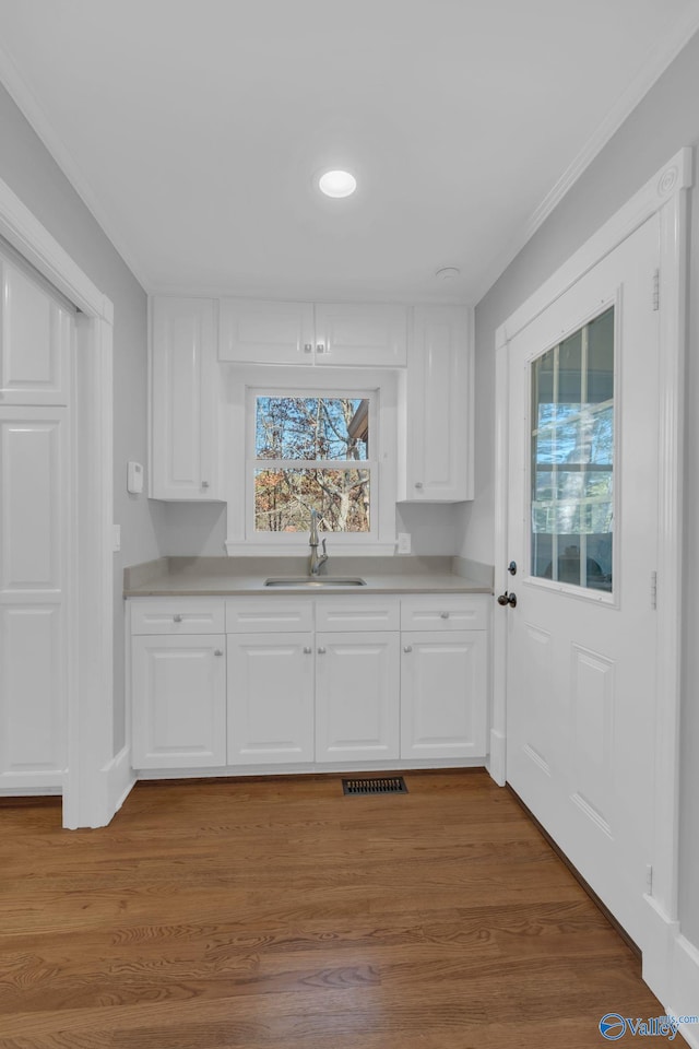 kitchen with a sink, visible vents, light countertops, and white cabinetry