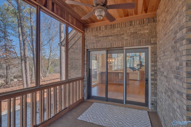 unfurnished sunroom featuring wooden ceiling, a ceiling fan, and a wealth of natural light