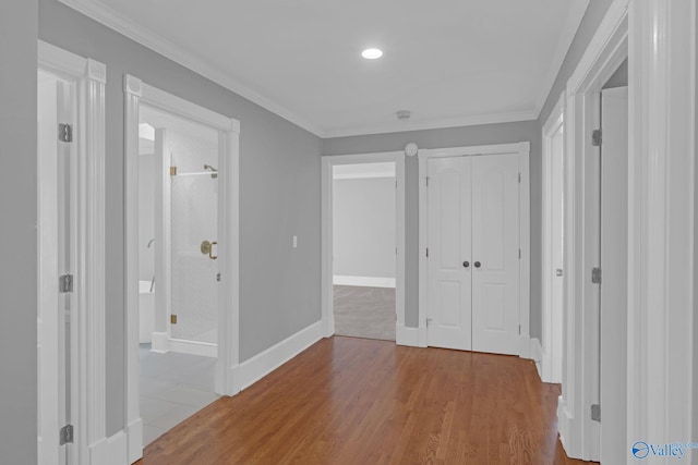 hallway featuring baseboards, wood finished floors, and ornamental molding