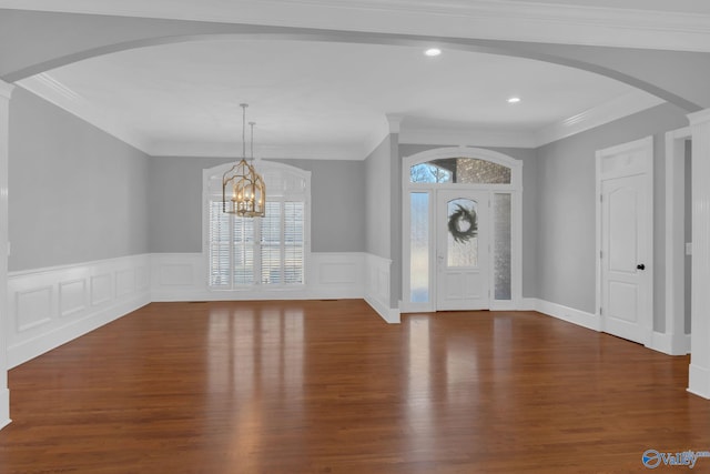 foyer featuring a wealth of natural light, wainscoting, wood finished floors, and crown molding