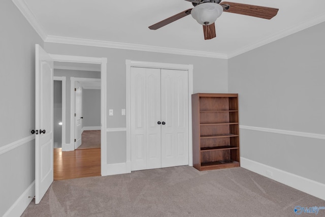 unfurnished bedroom with a closet, ornamental molding, baseboards, and carpet floors