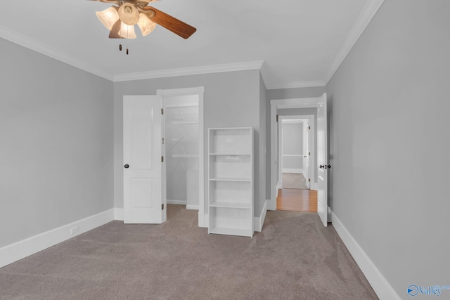 unfurnished bedroom with a walk in closet, baseboards, carpet floors, and crown molding