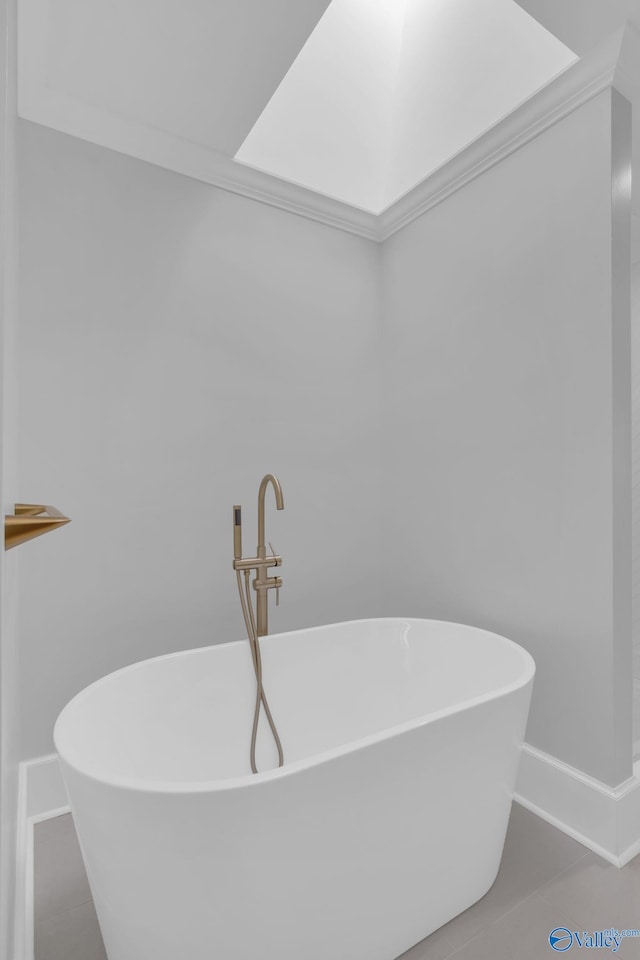 bathroom with a soaking tub, a skylight, and tile patterned floors