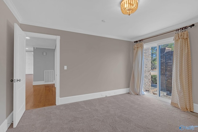 empty room with crown molding, carpet, visible vents, and baseboards