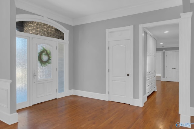 entrance foyer featuring a healthy amount of sunlight, crown molding, baseboards, and wood finished floors