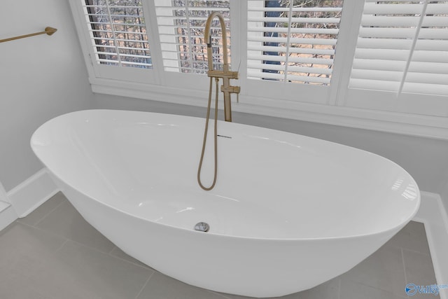 bathroom featuring a soaking tub, tile patterned floors, and a sink