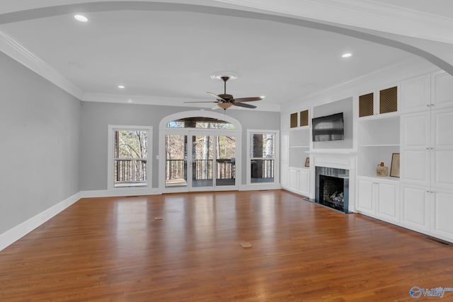 unfurnished living room featuring visible vents, a fireplace with flush hearth, wood finished floors, and crown molding