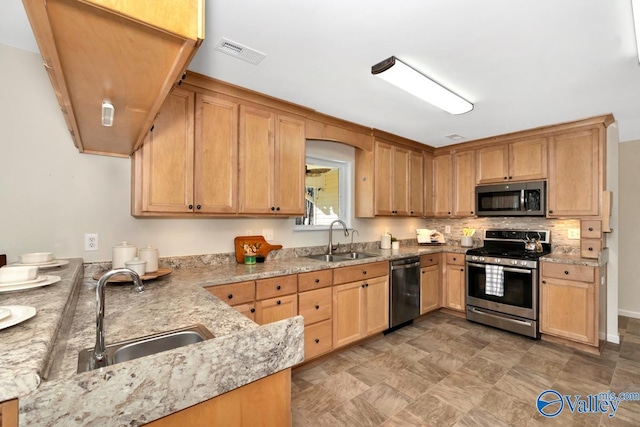 kitchen with a sink, stainless steel appliances, light stone countertops, and visible vents