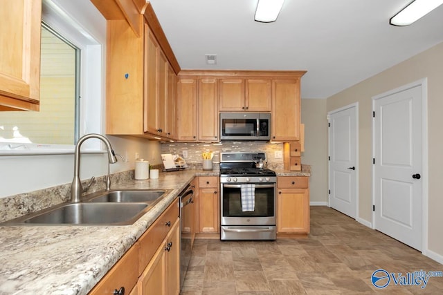 kitchen featuring tasteful backsplash, appliances with stainless steel finishes, baseboards, and a sink
