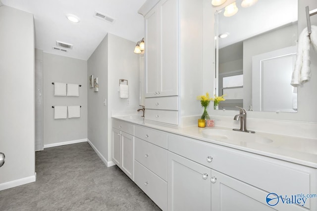 bathroom featuring double vanity, visible vents, baseboards, and a sink