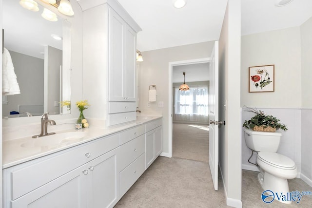 bathroom with double vanity, toilet, and a sink