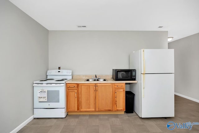 kitchen with white appliances, baseboards, visible vents, a sink, and light countertops