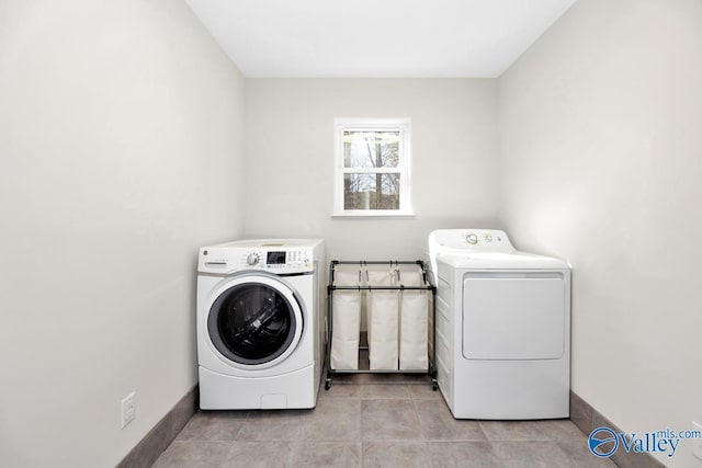 washroom featuring light tile patterned floors, laundry area, washing machine and dryer, and baseboards