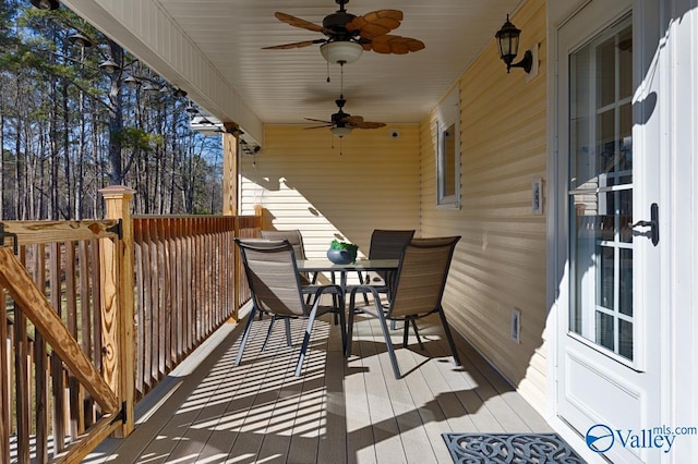 wooden terrace with outdoor dining area and ceiling fan