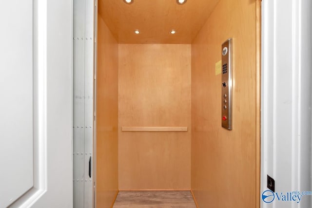 details featuring elevator, wood finished floors, and recessed lighting