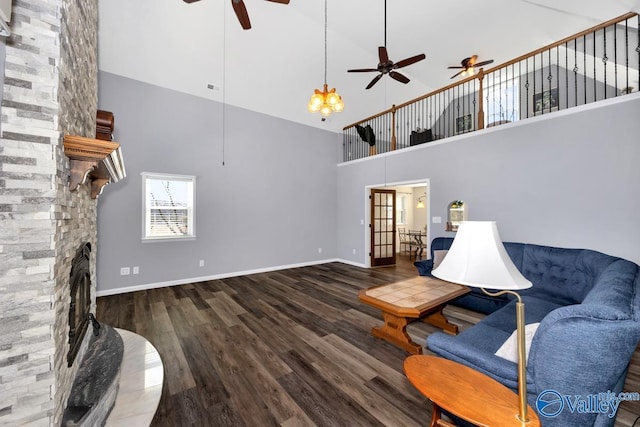 living room featuring wood finished floors, a ceiling fan, baseboards, visible vents, and a stone fireplace