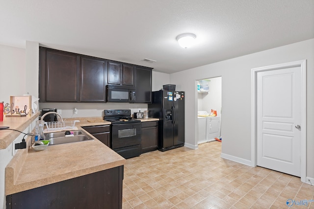 kitchen with black appliances, washer and dryer, dark brown cabinets, and sink