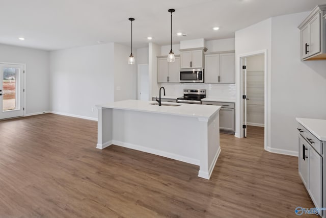 kitchen featuring gray cabinetry, sink, stainless steel appliances, dark hardwood / wood-style floors, and a kitchen island with sink