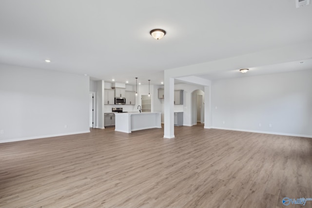 unfurnished living room with sink and light wood-type flooring