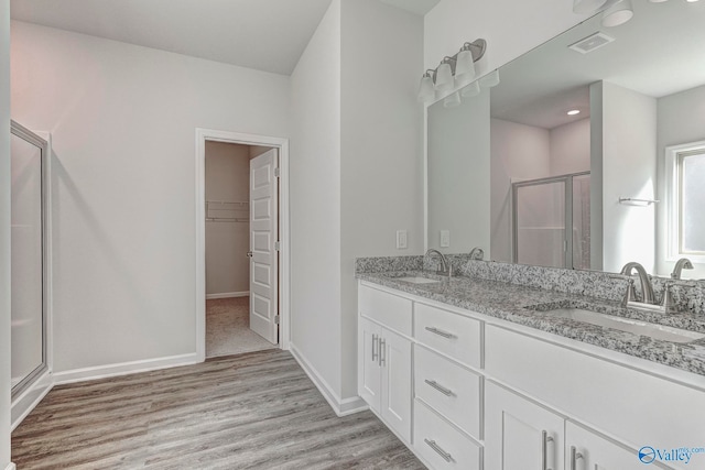 bathroom featuring wood-type flooring, vanity, and a shower with shower door