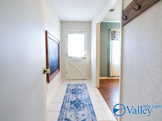 doorway to outside featuring light tile patterned flooring and a textured ceiling