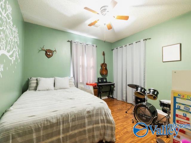 bedroom featuring ceiling fan, wood-type flooring, and a textured ceiling