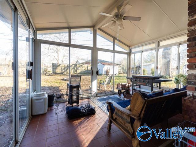 sunroom with ceiling fan and lofted ceiling with beams