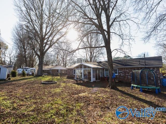 view of yard with a sunroom and a trampoline