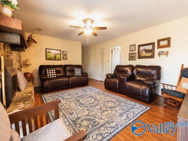 living room with a fireplace, wood-type flooring, and ceiling fan