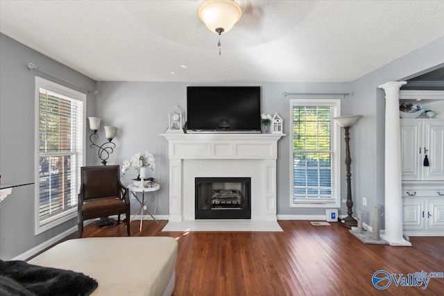 living room with a textured ceiling, ornate columns, a fireplace, and dark hardwood / wood-style flooring