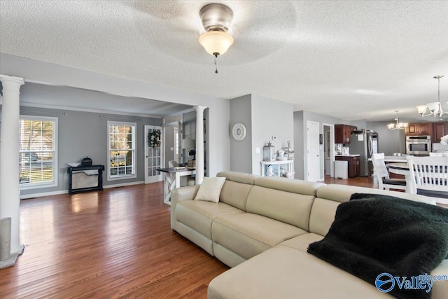 living room featuring decorative columns, a textured ceiling, ceiling fan with notable chandelier, and dark hardwood / wood-style flooring