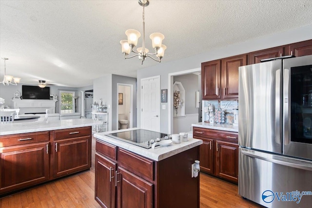 kitchen featuring light hardwood / wood-style floors, black electric cooktop, stainless steel fridge, and a kitchen island