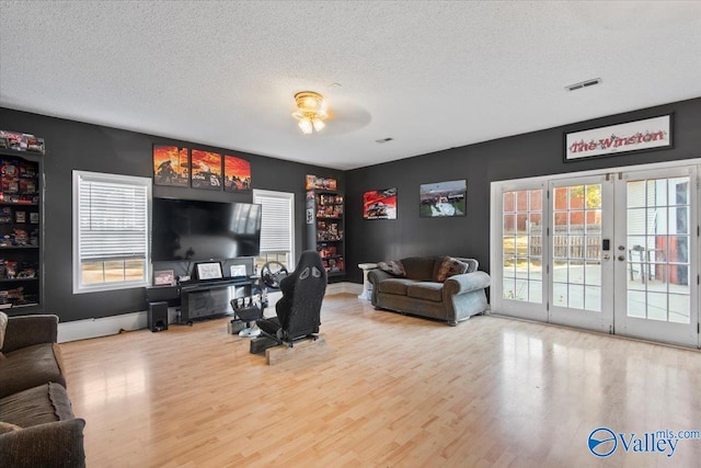 living room featuring french doors, hardwood / wood-style floors, a textured ceiling, and ceiling fan