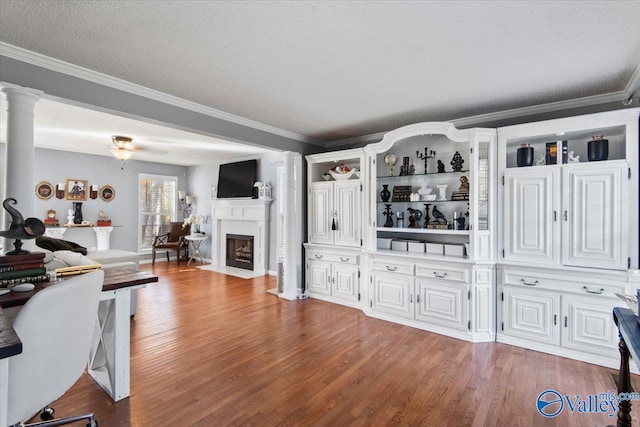 living room featuring light hardwood / wood-style flooring, a textured ceiling, ornate columns, and crown molding