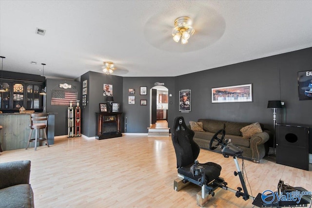 living room with a textured ceiling, hardwood / wood-style flooring, and ceiling fan