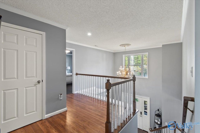 hallway with a notable chandelier, ornamental molding, a textured ceiling, and dark hardwood / wood-style flooring