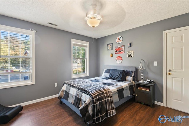 bedroom with dark hardwood / wood-style flooring, a textured ceiling, and ceiling fan