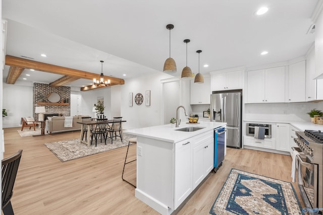 kitchen with an island with sink, light hardwood / wood-style flooring, stainless steel appliances, and white cabinets