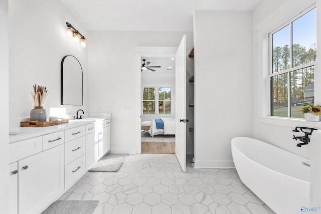 bathroom featuring vanity, a tub to relax in, a healthy amount of sunlight, and ceiling fan