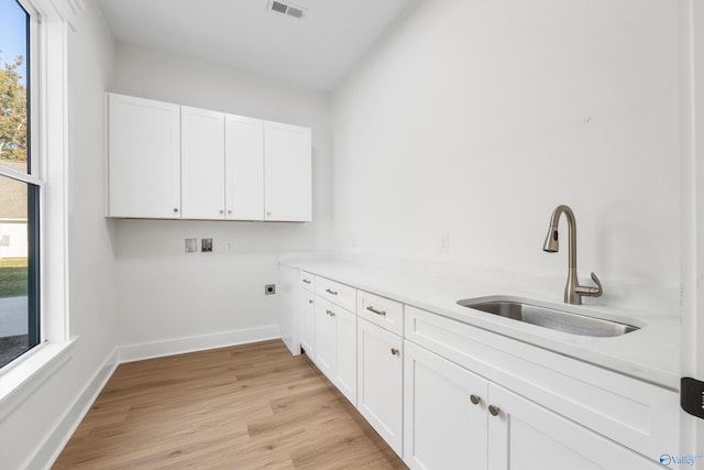 washroom featuring electric dryer hookup, washer hookup, a wealth of natural light, and light wood-type flooring